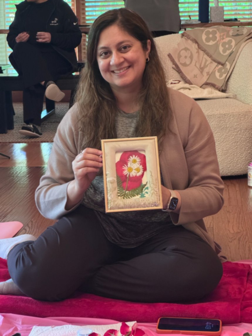Dr. Fatima Wasim holding a framed pressed-flower piece made during a retreat workshop